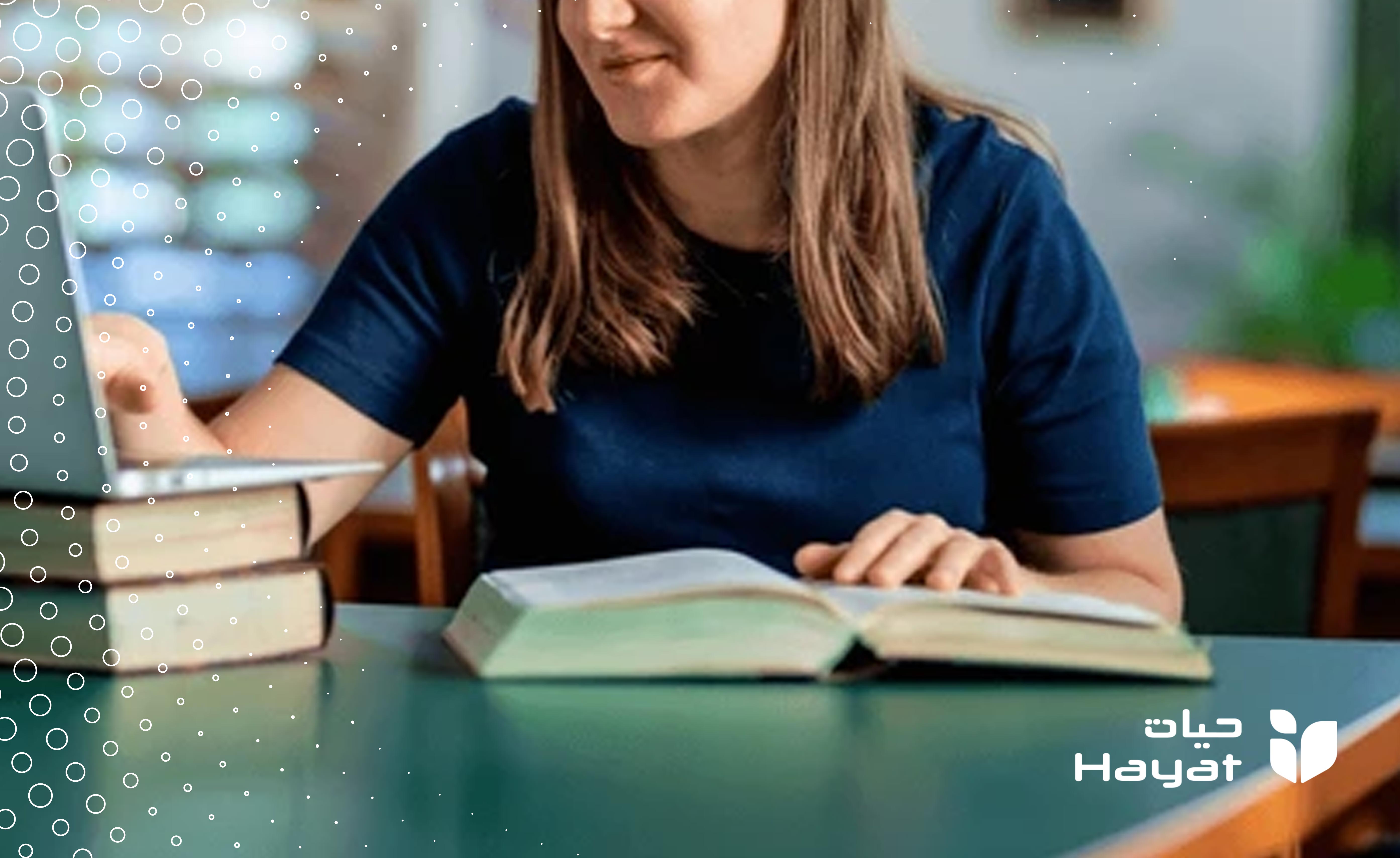 فتاة كفيفة تدرس بالجامعة، ممسكة بالحاسب الآلي بد، ويد اخرى ممسكة بكتاب