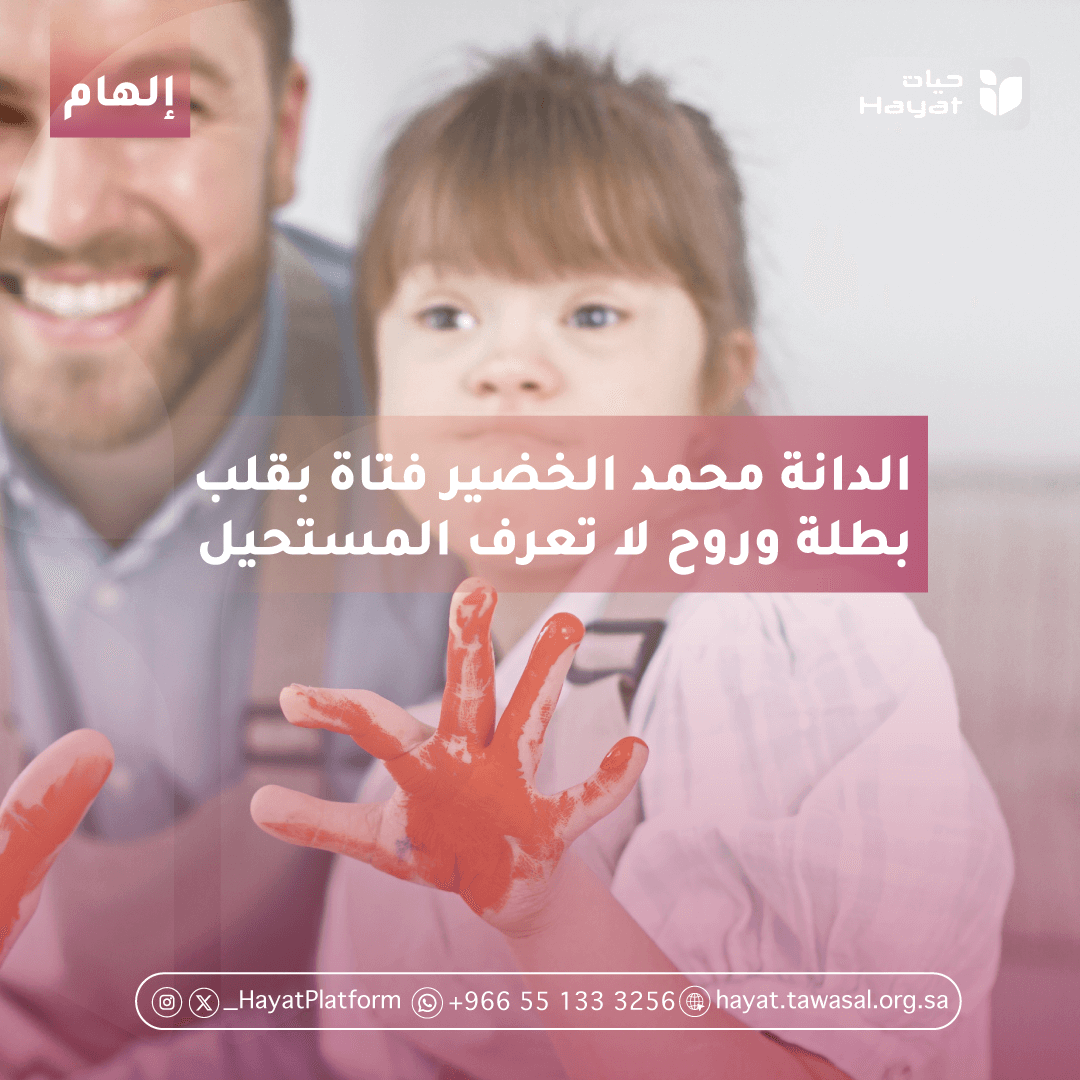   الصورة تظهر طفل متلازمة داون مبتسمة، تجلس بجانب رجل يبدو سعيدًا أيضًا. الطفلة ترفع يدها الملطخة بالألوان الحمراء.