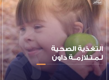 طفلة جميلة مصابة بمتلازمة داون تحمل معها تفاحة وهي مبتسمة